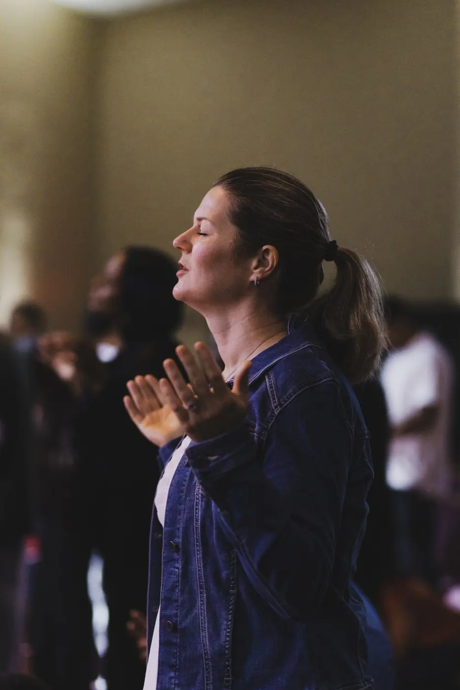 A woman worshipping with eyes closed