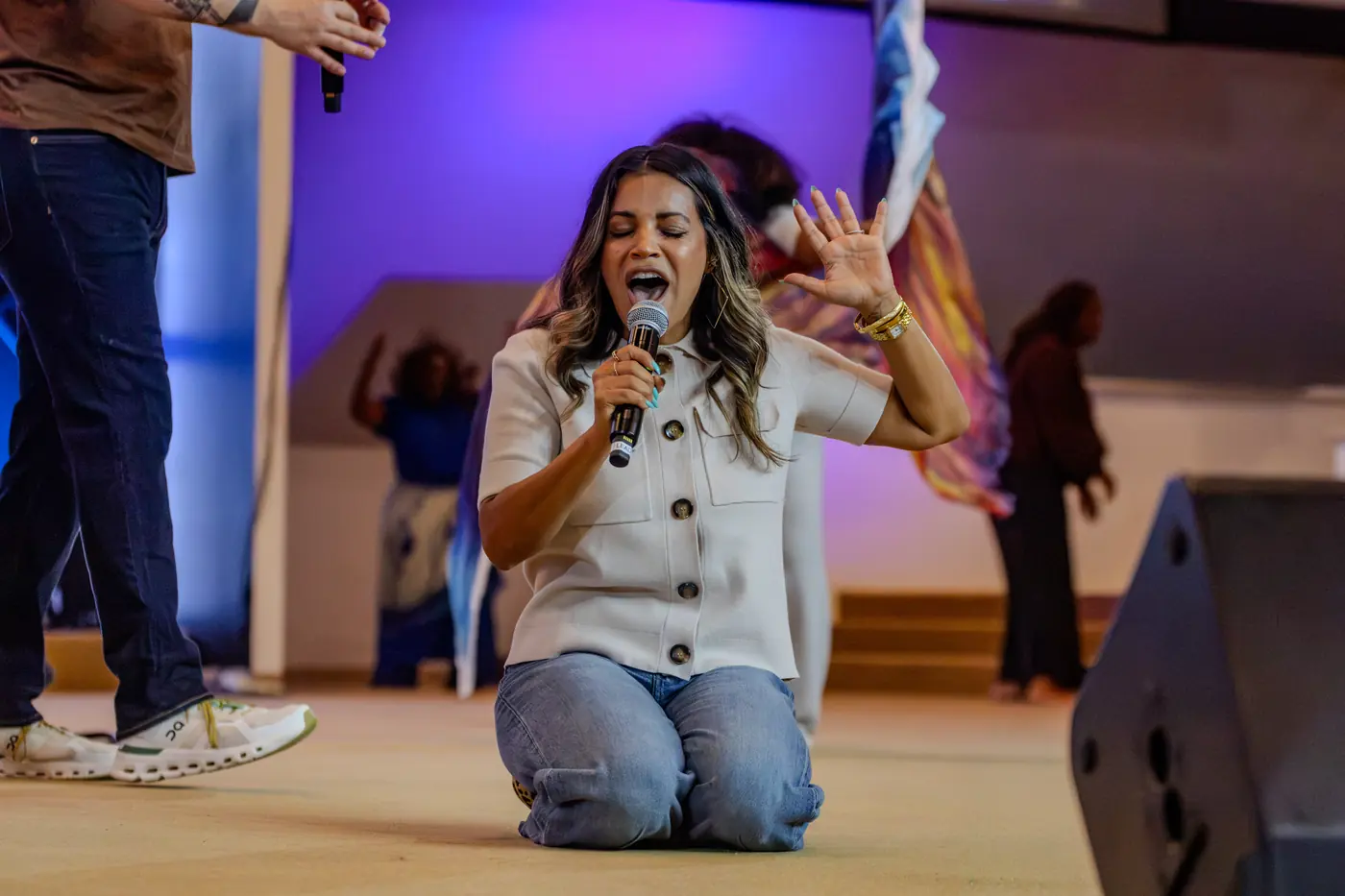 A worship leader kneeling on stage